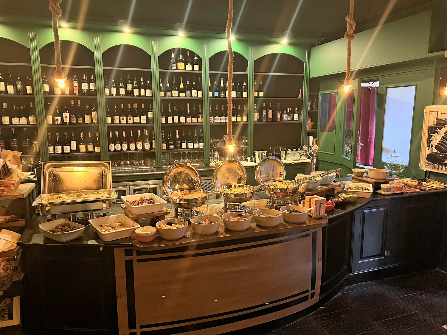 Il banco del buffet apparecchiato, con la parete dei vini sullo sfondo