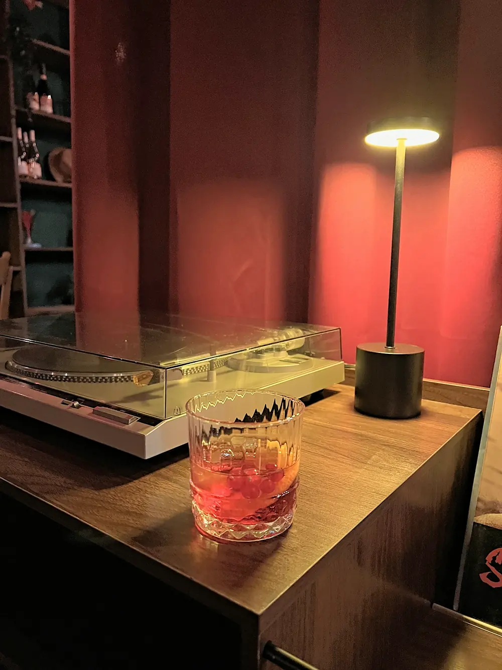 Un Negroni con ghiaccio accanto al giradischi e a una lampada da tavolo