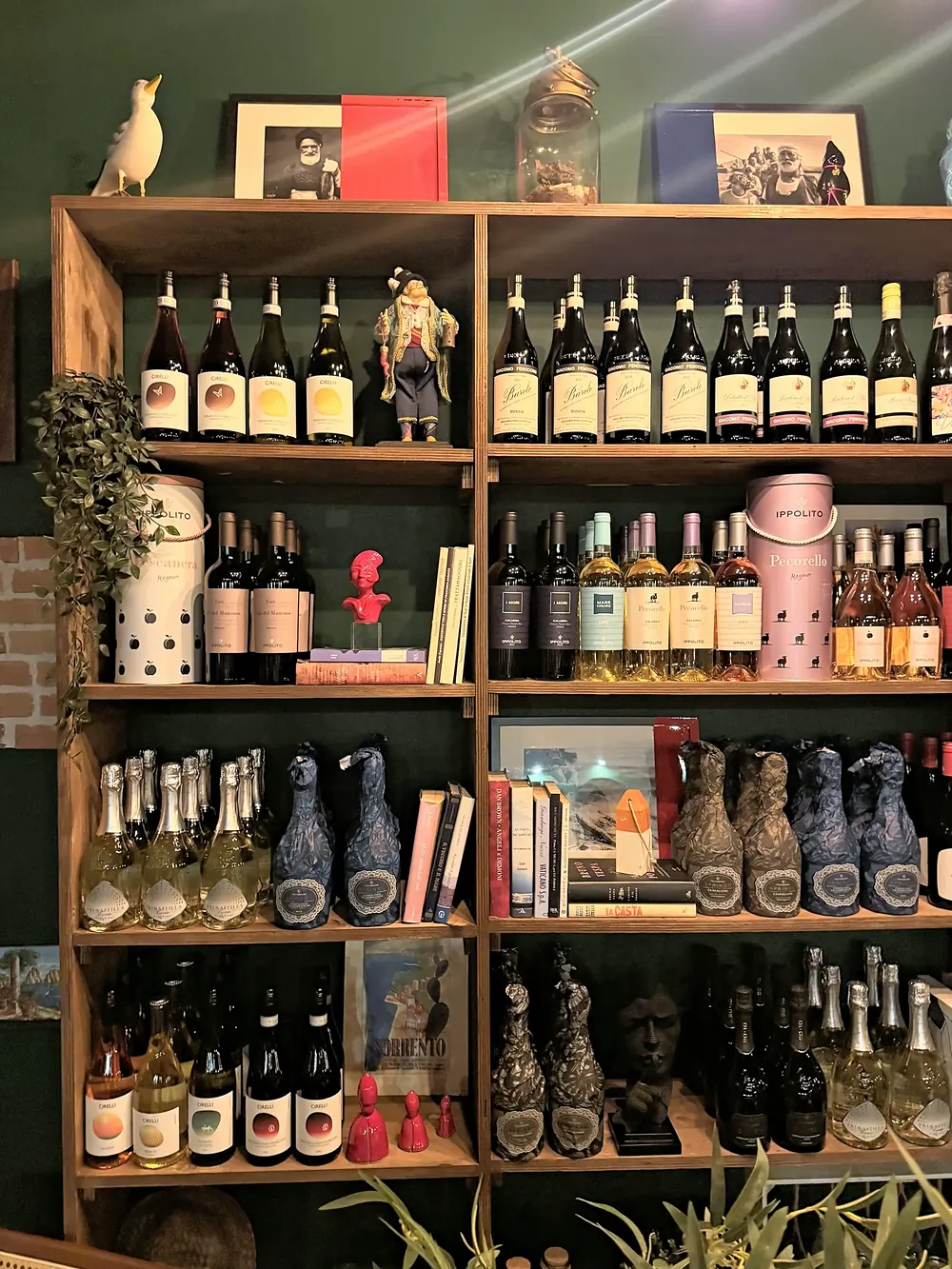 Uno scaffale con bottiglie di vino, libri e oggetti